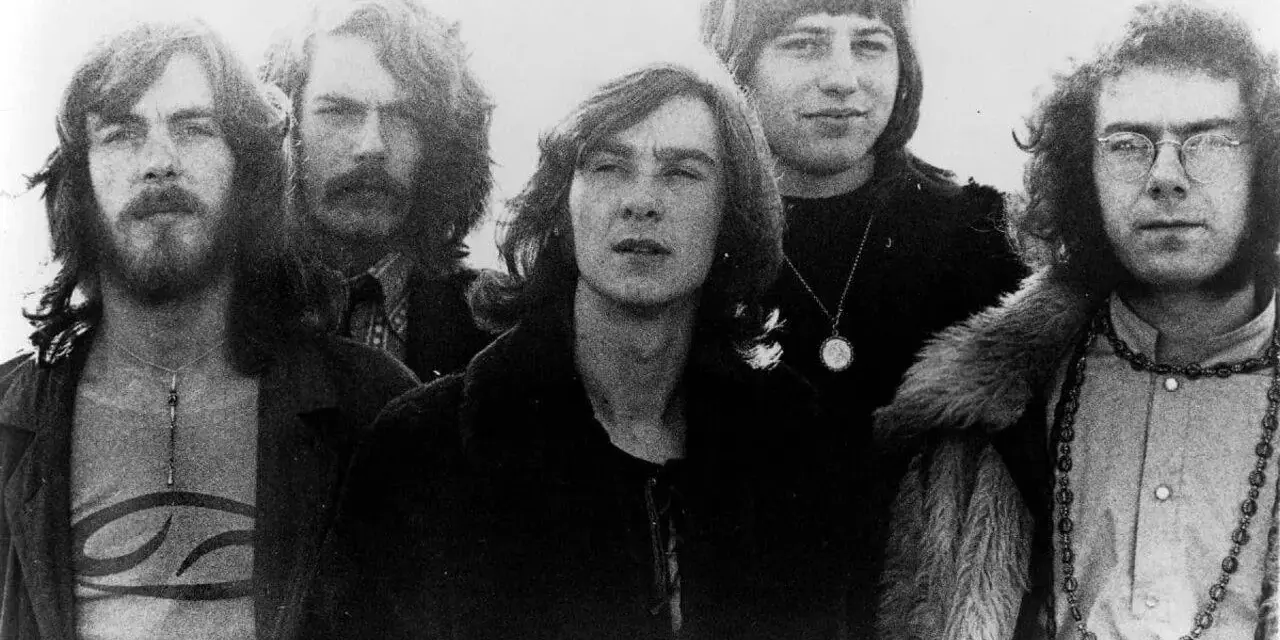 Cinq membres de King Crimson posent ensemble, arborant des coiffures et des vêtements typiques des années 70.