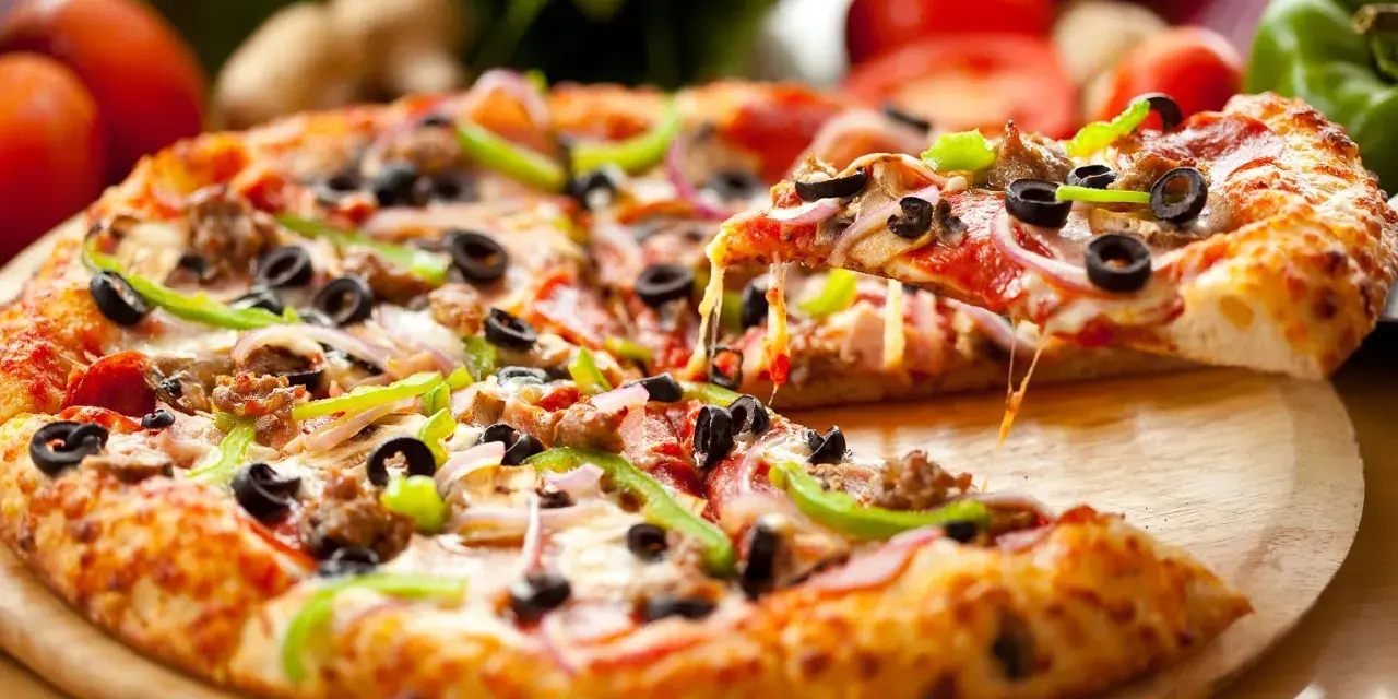 Pyszna pizza na gotowym cieście z Biedronki, z mnóstwem dodatków: mięsem, oliwkami, papryką i cebulą. Ser ciągnie się apetycznie.