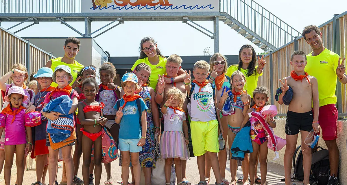 Un groupe d'enfants joyeux, portant des foulards orange, pose pour une photo de famille lors de leurs vacances.