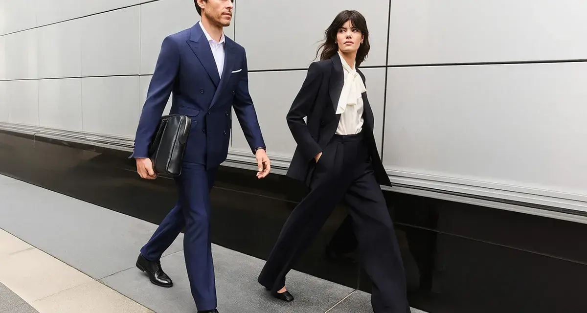 Para idąca w eleganckim business attire, mężczyzna w granatowym garniturze, kobieta w czarnym.