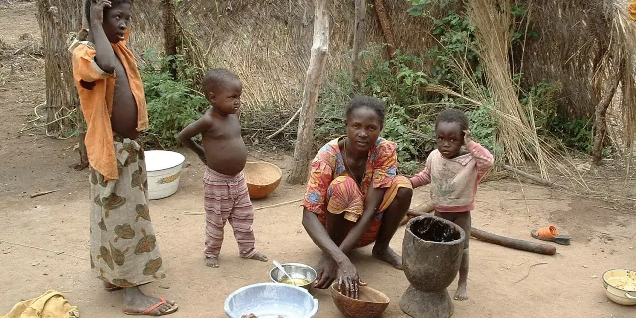 Dzieci i matka w tradycyjnej chacie w Burkina Faso. Kobieta przygotowuje posiłek, a dzieci obserwują.