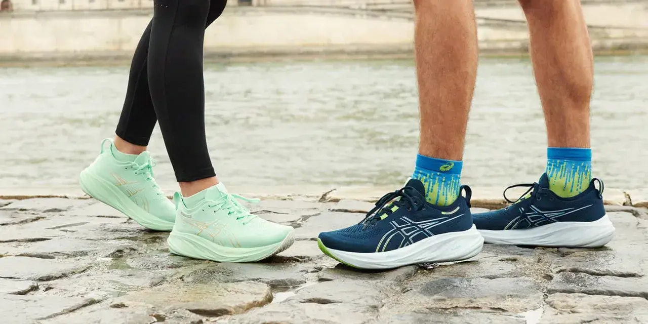 Två par löparskor, mintgröna Asics Gel Luminus 2 dam och mörkblå herrskor, står på stenar vid en flod.