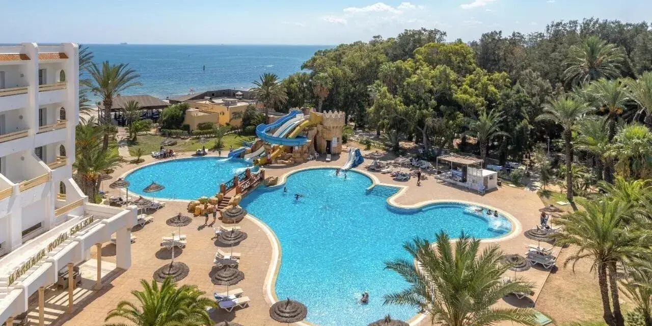 Basen z wodnymi zjeżdżalniami i palmami przy hotelu, idealne miejsce na wakacje. Wiele osób korzysta z uroków tego miejsca, co potwierdzają pozytywne marhaba club opinie.