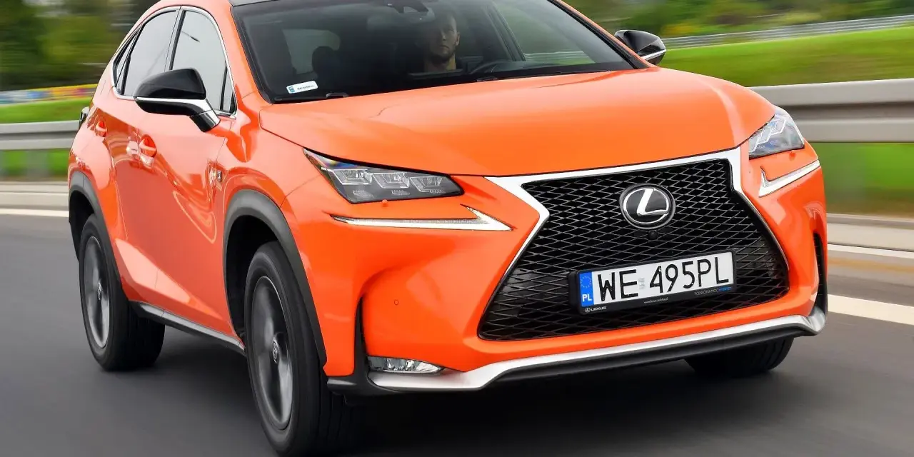 Pomarańczowy Lexus NX 300 jedzie po drodze, kierowca widoczny za kierownicą.