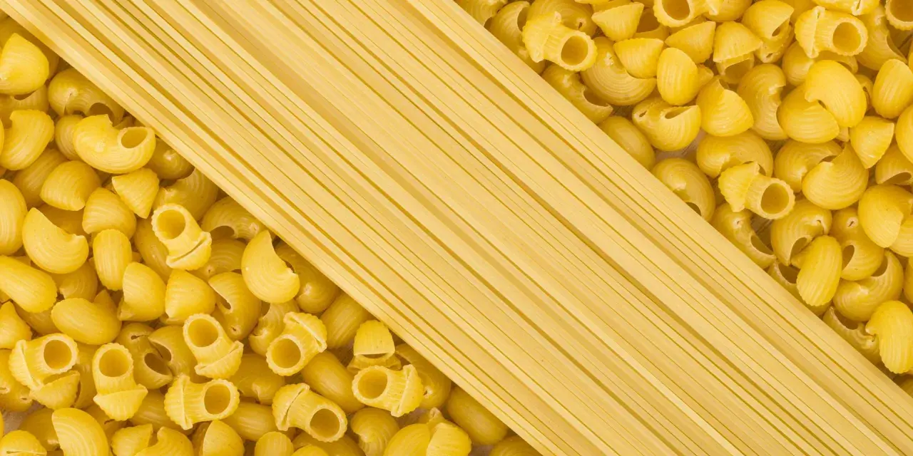 Makaron proteinowy w formie długich nitek obok tradycyjnego makaronu w kształcie muszelek.