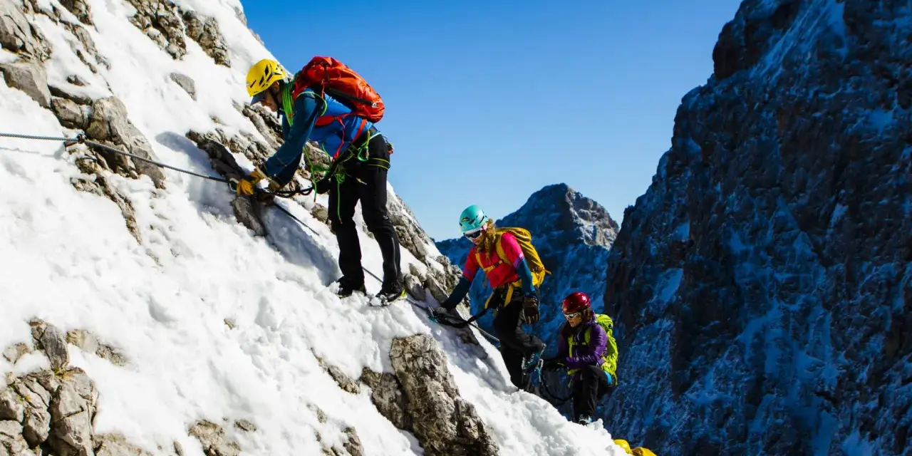 Drei Bergsteiger meistern den Klettersteig Zugspitze im Schnee.