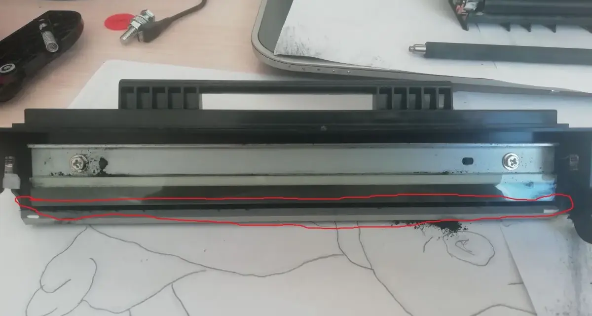 Rozłożony sp112 toner z widocznym wałkiem i resztkami proszku. Czerwona linia zaznacza uszkodzony element.