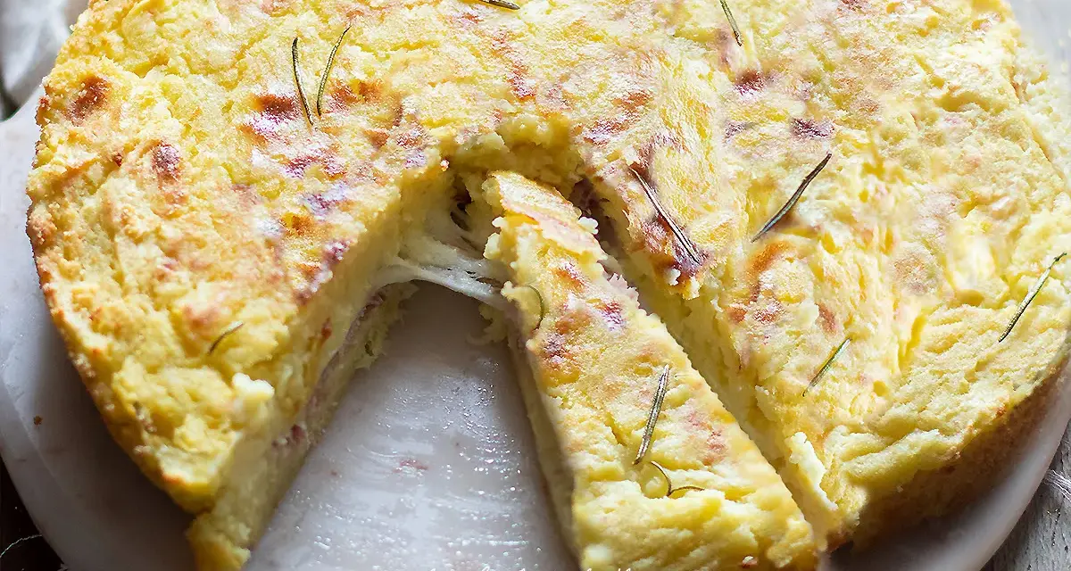 Una fetta di torta di patate filante, dorata e profumata al rosmarino, pronta per essere gustata.