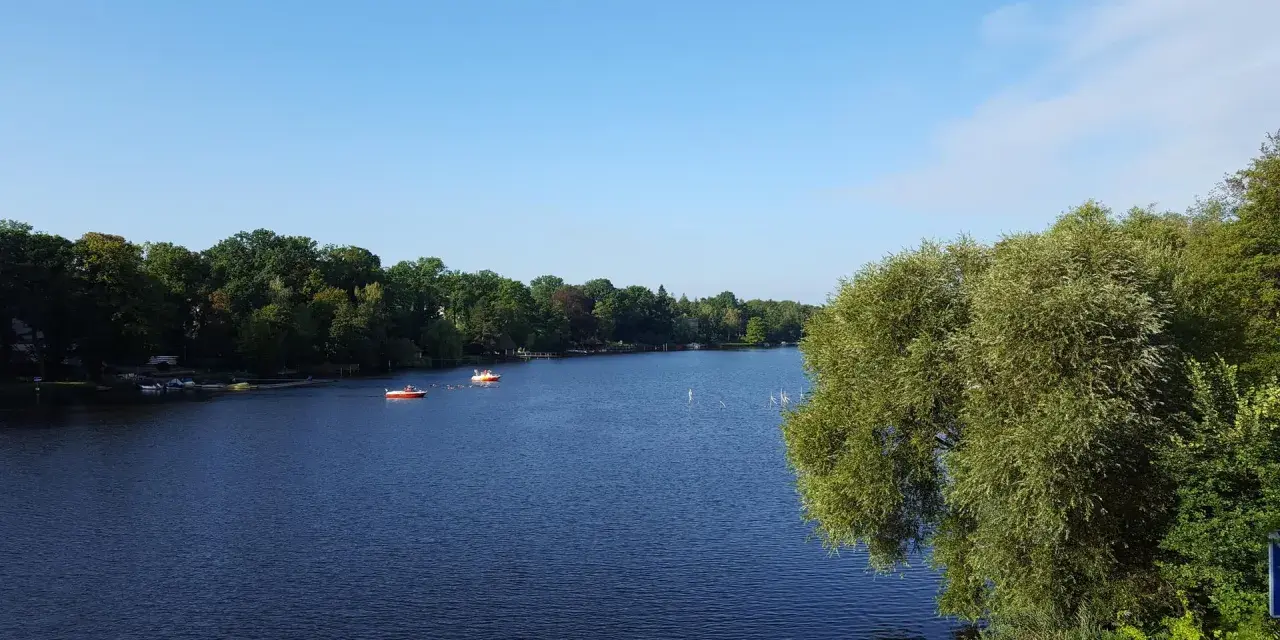 Ein ruhiger See mit Booten, umgeben von grünen Bäumen. Ein perfekter Ort für einen entspannten Tag, ein echter Geheimtipp in Berlin.