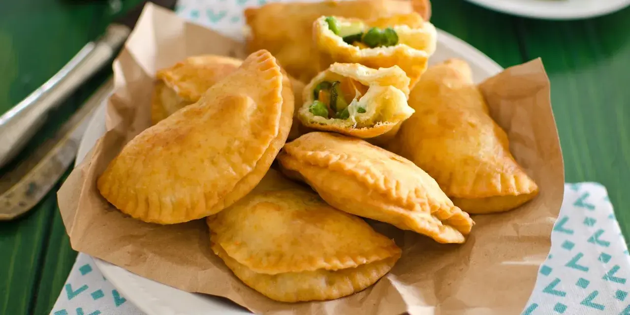 Panzerotti al forno dorati e ripieni di verdure, serviti su carta da forno.