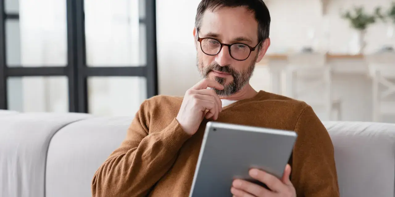 Mann sitzt nachdenklich auf Sofa, sein Samsung Tablet geht nicht mehr an.