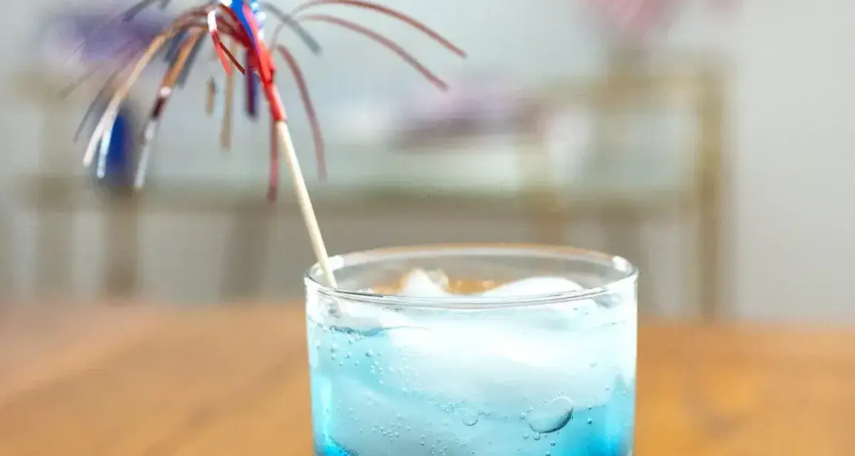 Orzeźwiający drink z grenadyną i blue curacao, ozdobiony kolorową parasolką, idealny na letnie popołudnie.