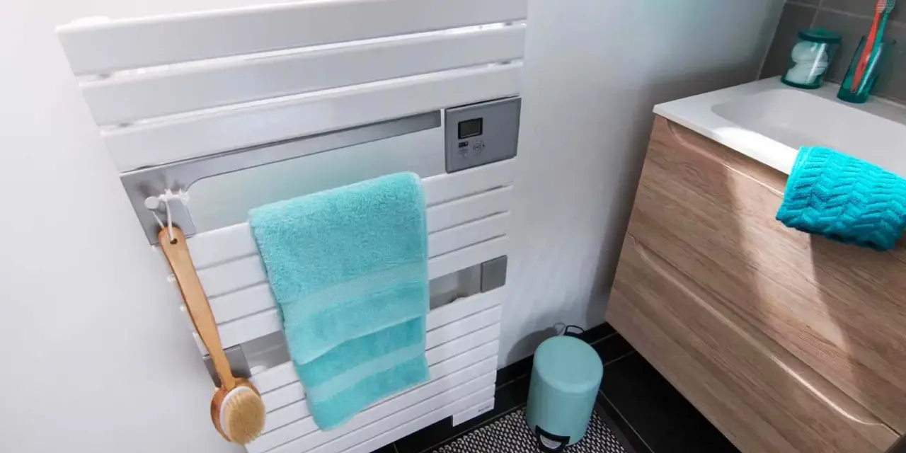 Un sèche-serviettes blanc moderne, avec une serviette turquoise et une brosse de bain en bois. La hauteur du sèche-serviette est idéale pour un accès facile.