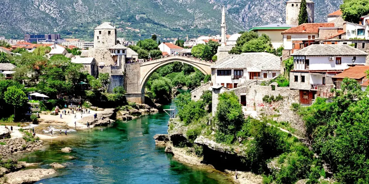 Mostar, Bośnia i Hercegowina. Tłumy ludzi spacerują po Starym Moście, a turkusowa rzeka Neretwa płynie poniżej. Czy Bośnia i Hercegowina jest bezpieczna? Tak, to piękny kraj.