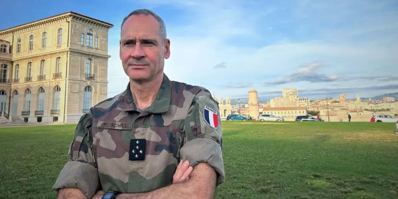 Un officier français, P. Schill, pose devant un bâtiment historique. Comment retrouver un officier ? Il suffit de regarder son uniforme et son insigne.