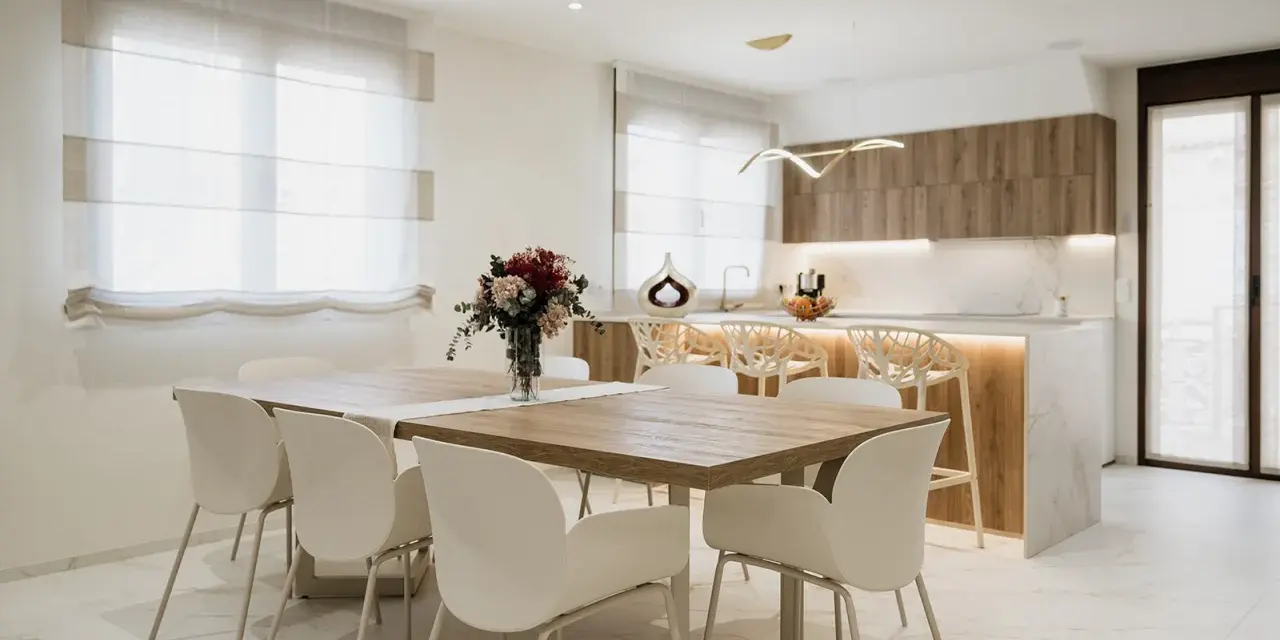 Elegantes cocinas abiertas al salón con barra, mesa de comedor y sillas blancas.