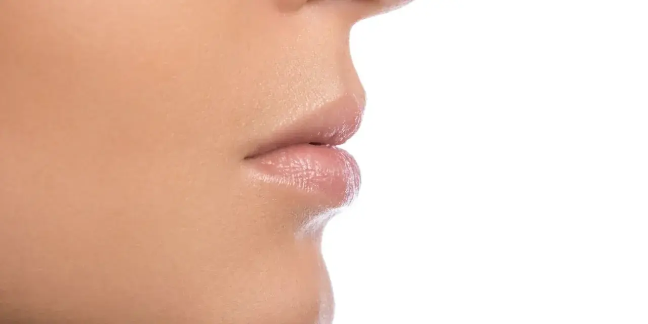 Primer plano de la nariz y los labios de una persona, mostrando la textura de la piel y los filamentos sebáceos en la nariz.