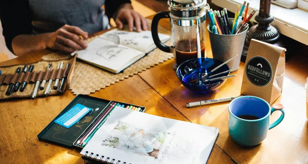 Kreative Inspiration am **cafe impuls**: Skizzenbuch, Stifte, Kaffee und eine Tasse laden zum Malen ein.