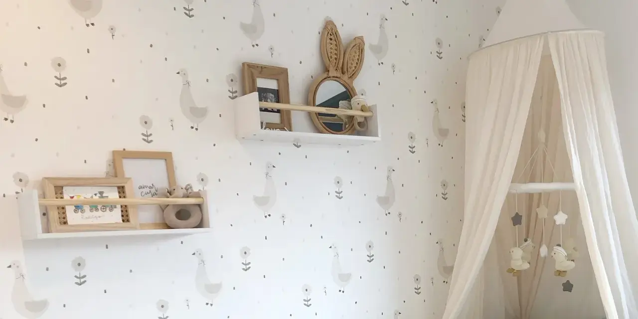 Habitaciones con papel pintado y pintura de patitos y flores. Un dosel de cama blanco cuelga sobre una cuna.