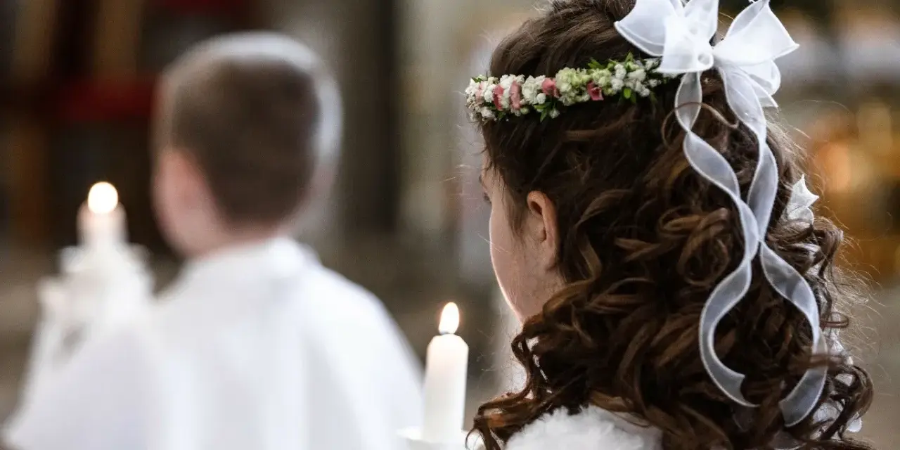 Dziewczynka z wiankiem na głowie i wstążkami we włosach trzyma świecę. Obok niej chłopiec, też z zapaloną świecą. To ważny dzień, biały tydzień.