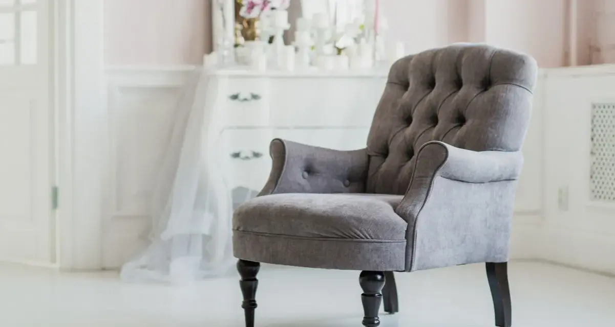 Elegante sillón gris con botones, ideal para un tocador. ¿Cuánto vale tapizar una silla así?