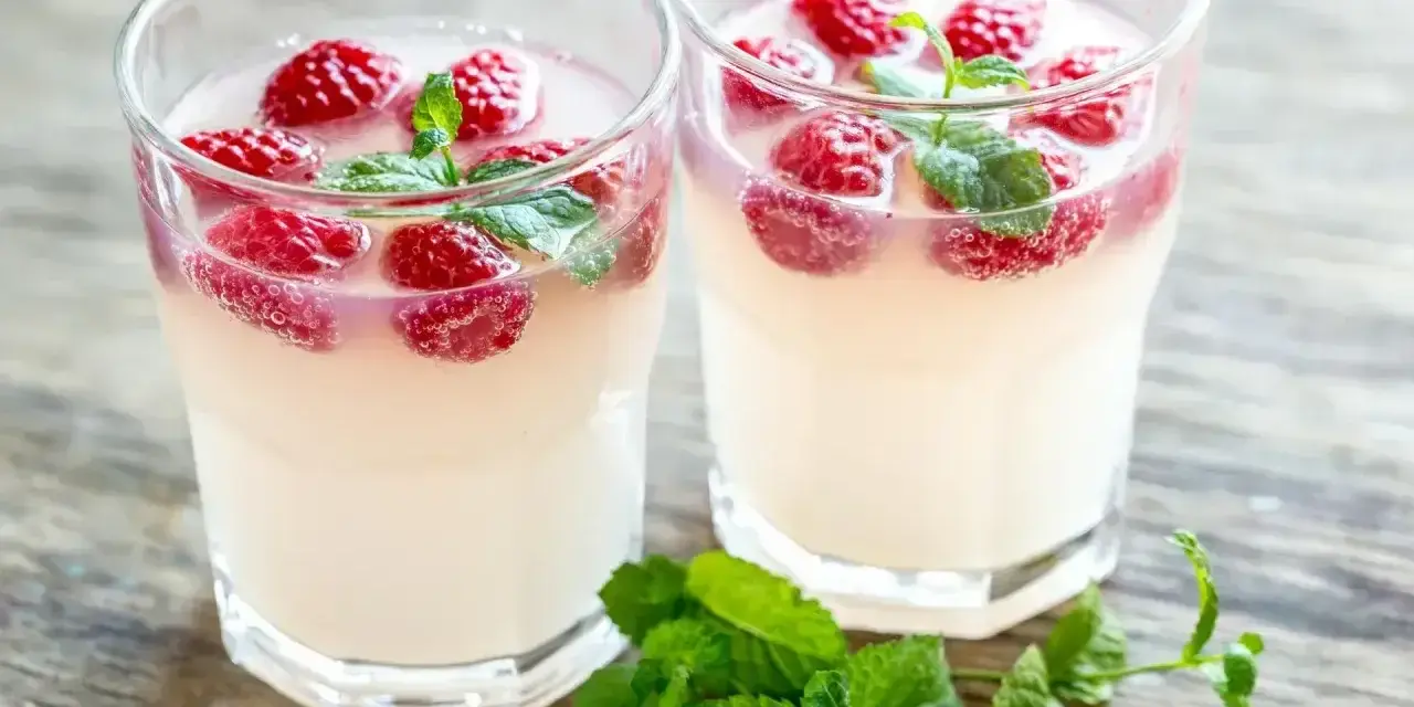 Dwa orzeźwiające drinki z malinami i miętą, idealne na letnie popołudnie. Wyglądają jak pyszne bacardi malinowe.