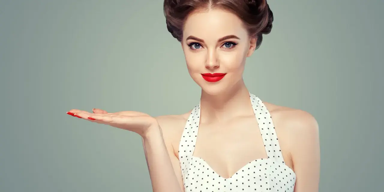 Kobieta w stylu pin-up z burzą loków i czerwoną szminką prezentuje dłoń.