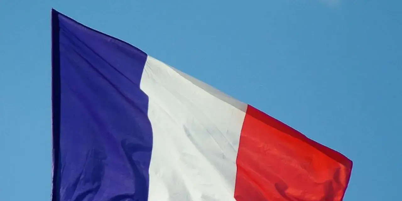 La bandera de Francia ondea con orgullo contra un cielo azul claro.