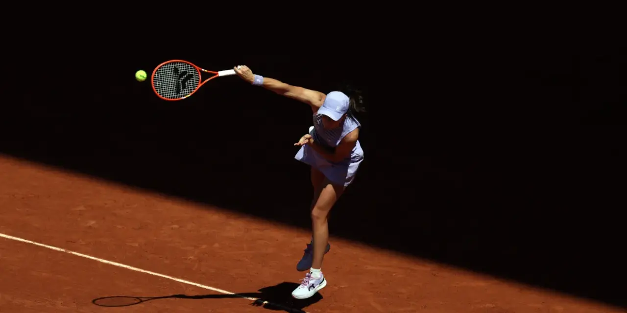 Tenisistka w skoku serwuje piłkę na korcie ziemnym podczas Roland Garros.