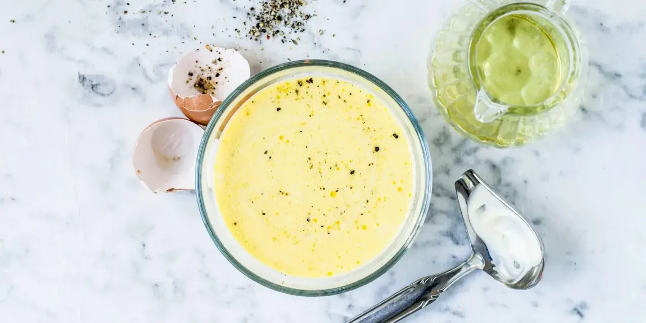 Zutaten für eine cremige french dressing: Eierschalen, Pfeffer, Öl und eine Schüssel mit der fertigen Soße.