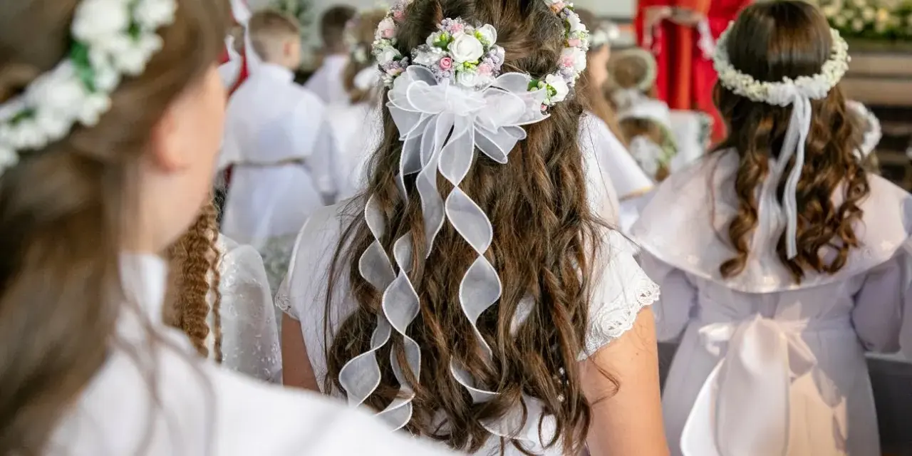 Dzieci w białych strojach, z wiankami na głowach, czekają na swoją pierwszą komunię. Wzruszający moment w kościele.