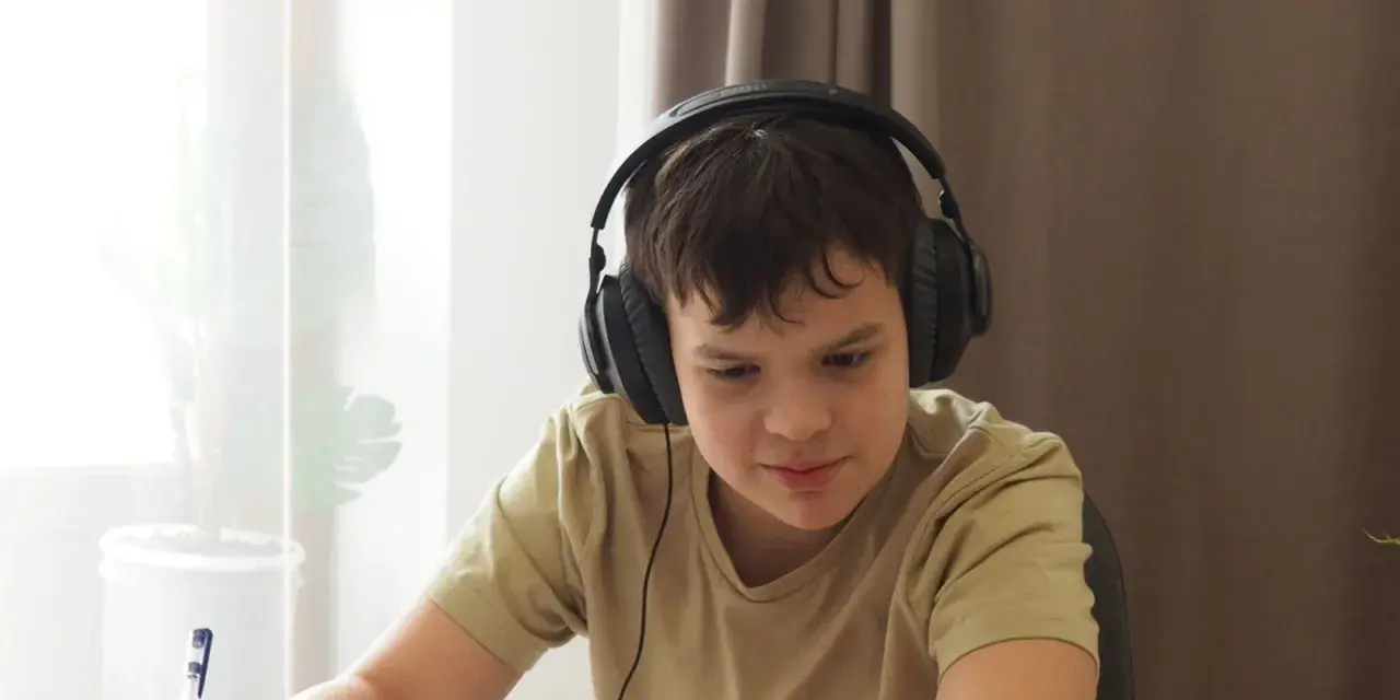 Chłopiec w słuchawkach uczy się zdalnie, notując. Dopełnienie odpowiada na pytania: kogo? czego? komu? czemu? kogo? co? czym? kim? o kim? o czym?