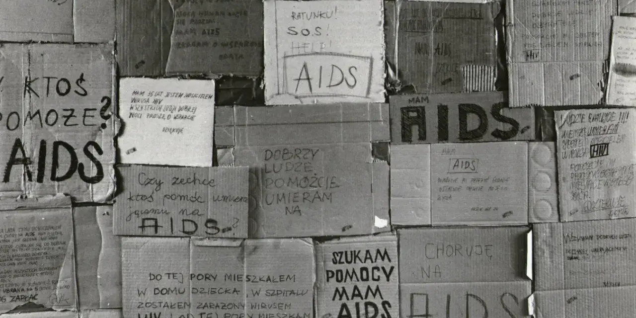 Złe ojciec, zniszczony przez AIDS, błaga o pomoc. Kartony z napisami "AIDS", "SOS", "Ratunku!" i prośbami o wsparcie.