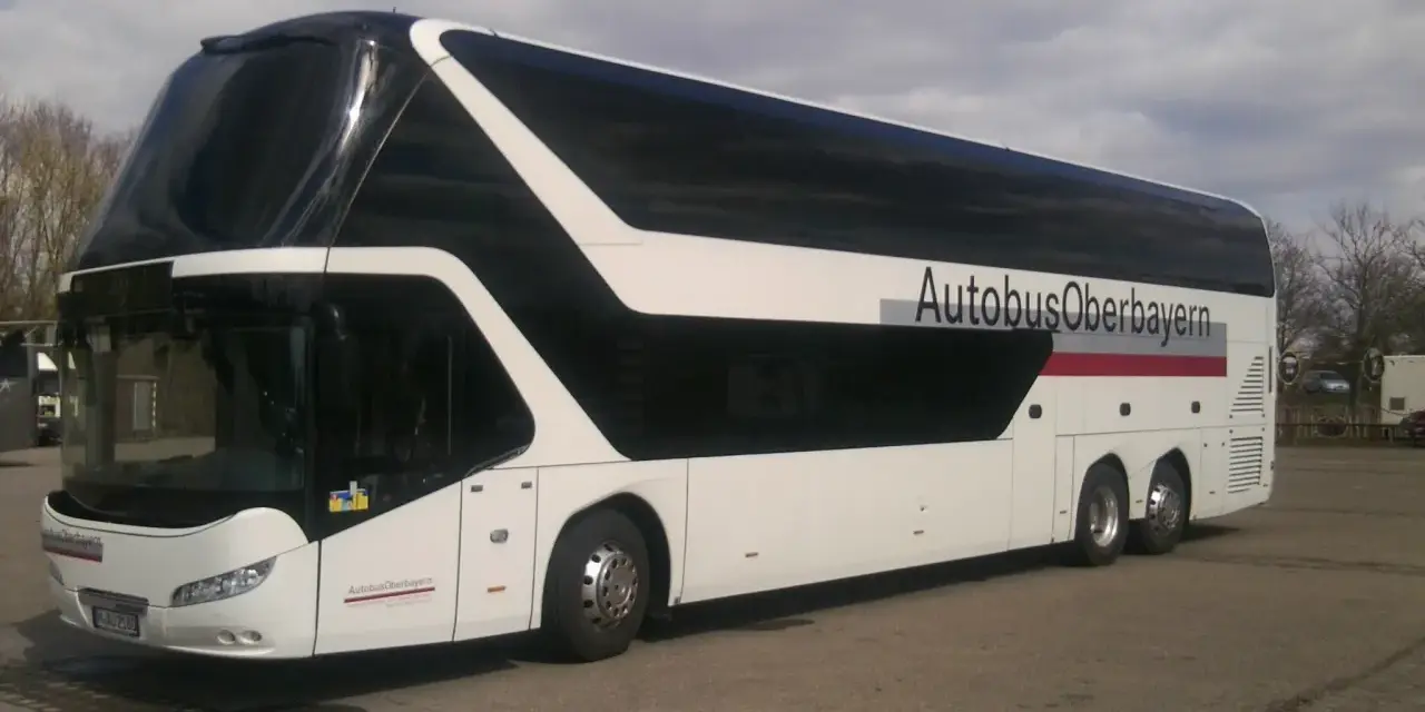Biały autokar piętrowy z czarnymi oknami i napisem "AutobusOberbayern".