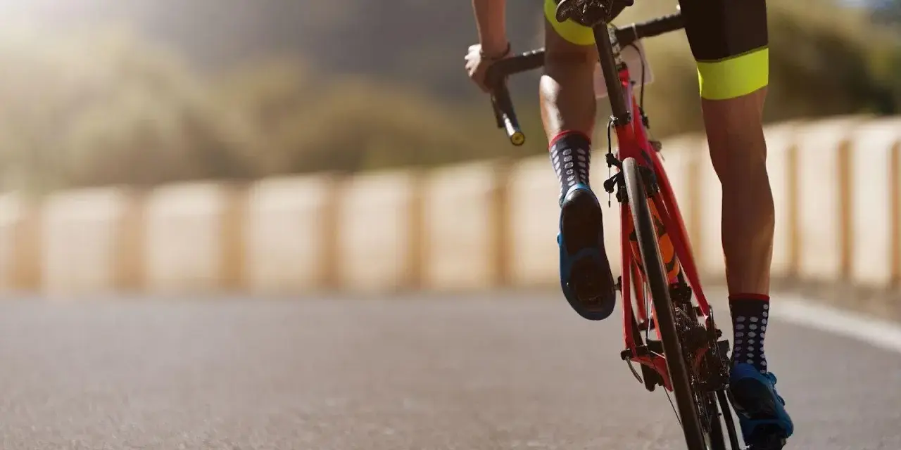 Cyclist in neon-accented shorts and polka-dot socks powering up a hill, embodying a dedicated sprint workout plan.