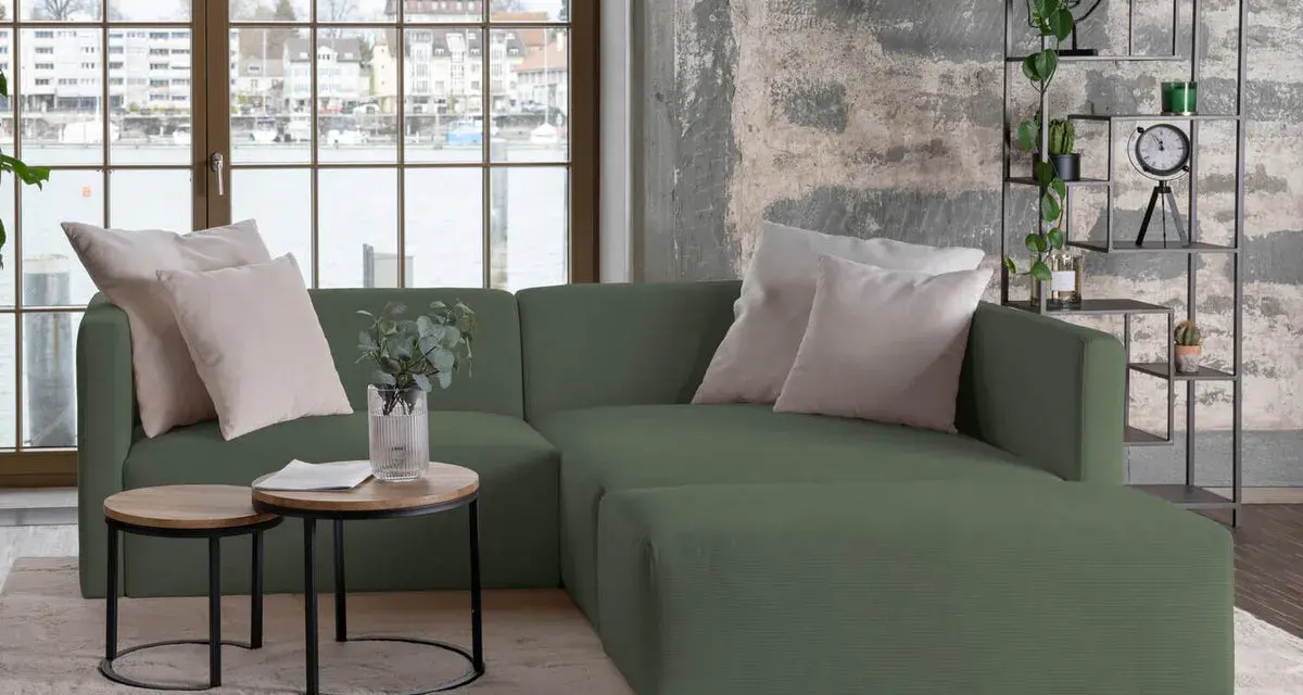 Divani verdi in colori di tendenza, con cuscini chiari e tavolini rotondi. Un angolo relax moderno con vista sul lago.