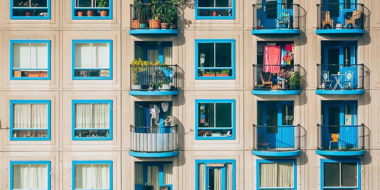 Elegancka loggia i balkon z niebieskimi ramami okiennymi na betonowej fasadzie budynku.