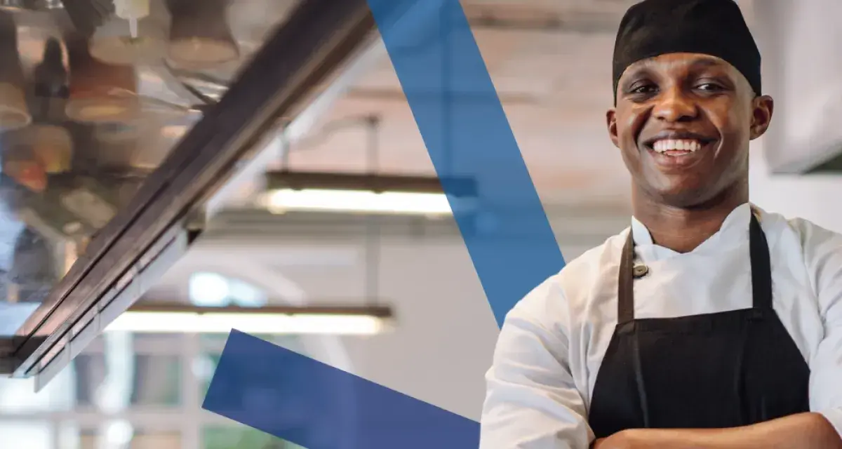 Chef sonriente con delantal negro, listo para servir. Conoce los derechos y obligaciones de un camarero.