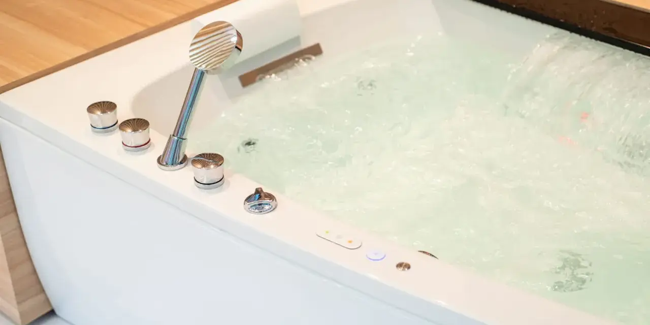 Bain bouillonnant avec jets d'eau et douchette chromée, prêt pour un moment de détente dans ce spa balnéo.