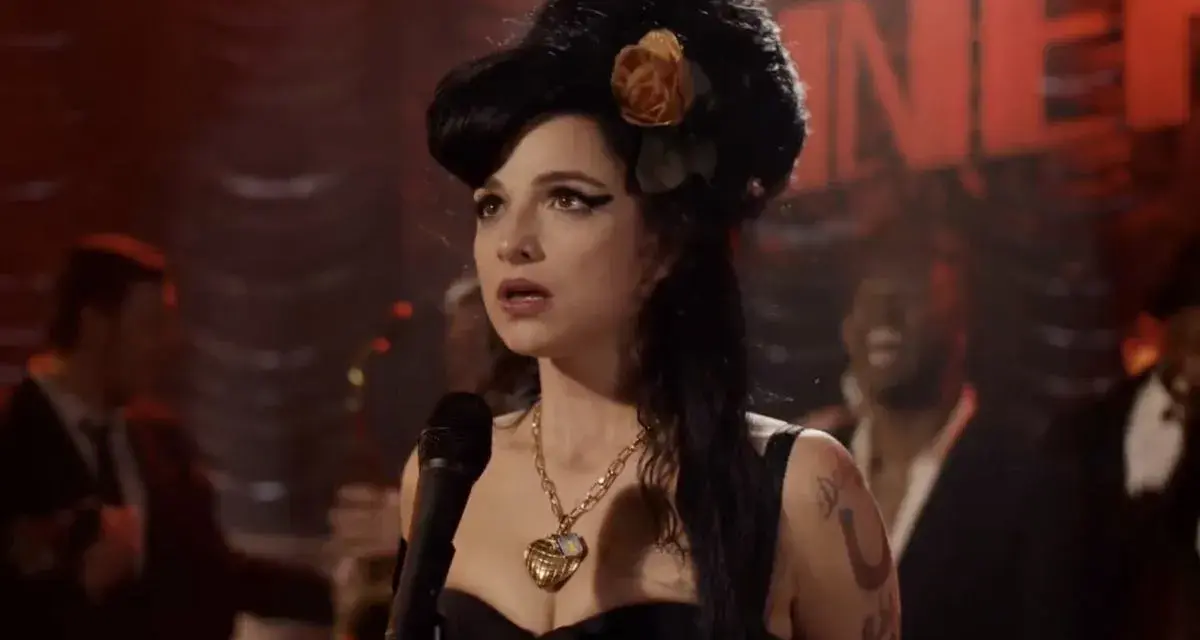 Aktorka wcielająca się w Amy Winehouse na scenie, w charakterystycznej fryzurze i z naszyjnikiem. Scena przypomina fragmenty z filmów o jej życiu.