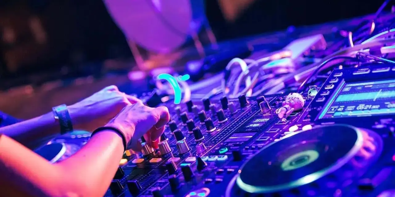 Hände am DJ-Pult, die die Regler für verschiedene techno genres bedienen. Neonlicht und pulsierende Beats.