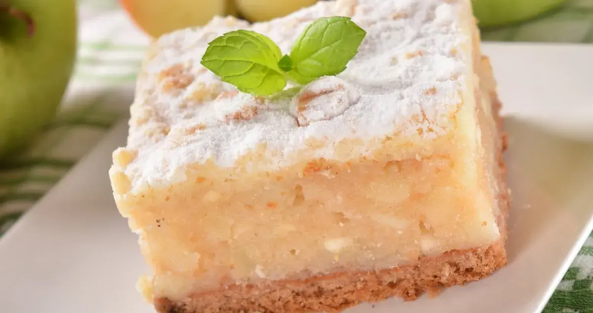 Pyszne, ekspresowe ciasto z jabłkami, posypane cukrem pudrem i udekorowane listkiem mięty. Idealne na szybki deser.