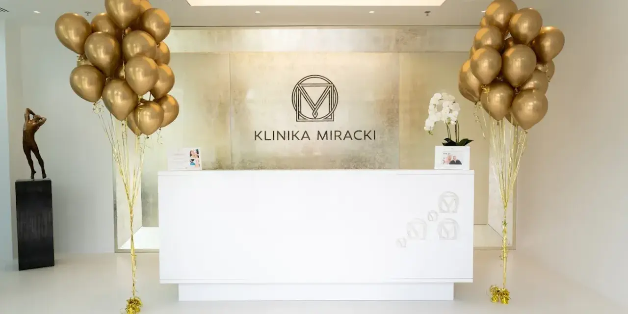 Recepcja kliniki z bukietami złotych balonów i rzeźbą.