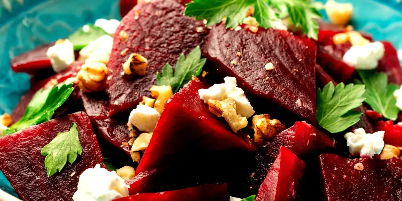 Ein köstlicher Rote Bete Feta Salat mit Nüssen und frischer Petersilie, serviert in einer blauen Schüssel.