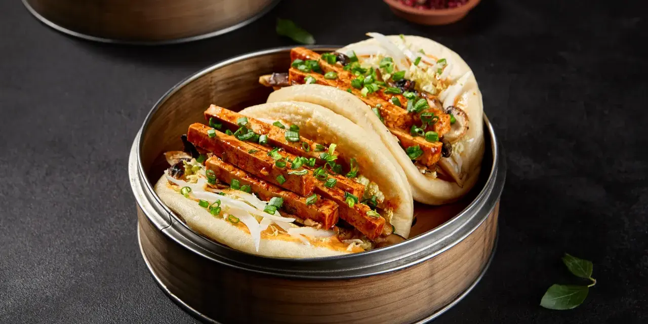 Pierożki baozi z tofu i warzywami, podane w bambusowym parowniku.