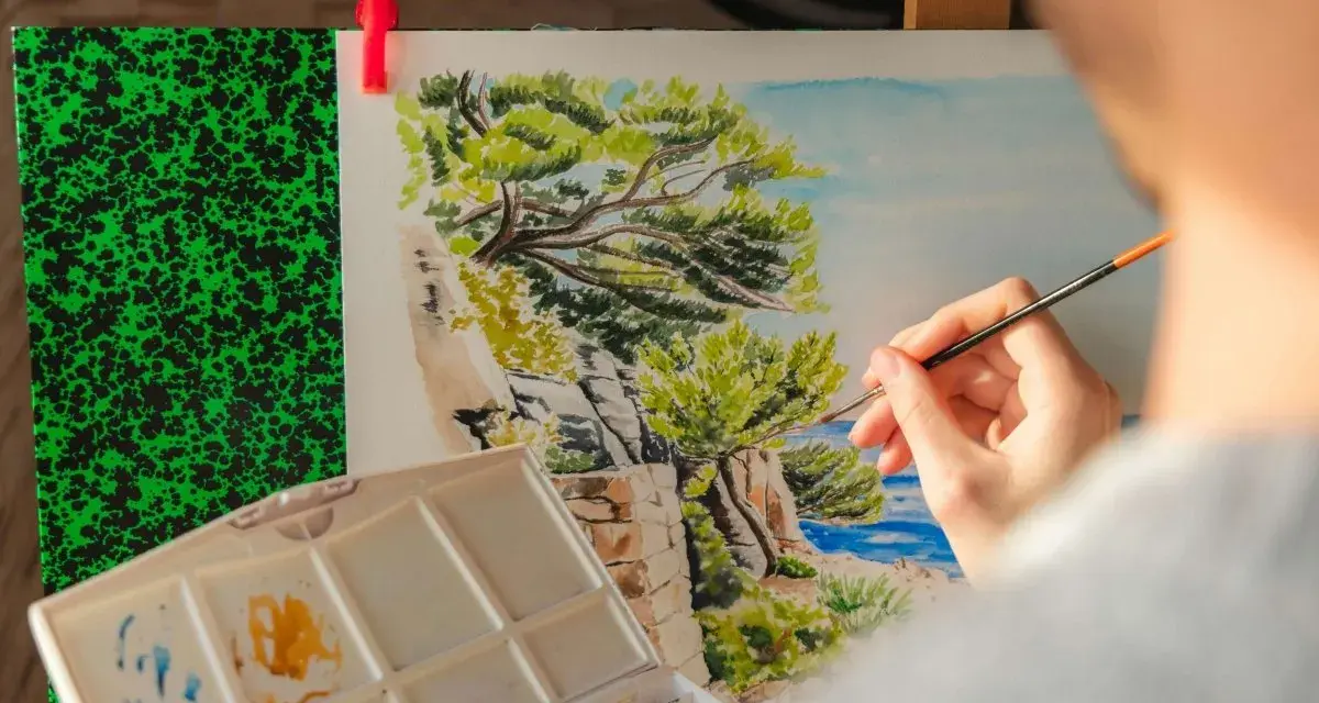 Une main peint un paysage marin, une excellente idée peinture facile pour capturer la beauté de la nature.