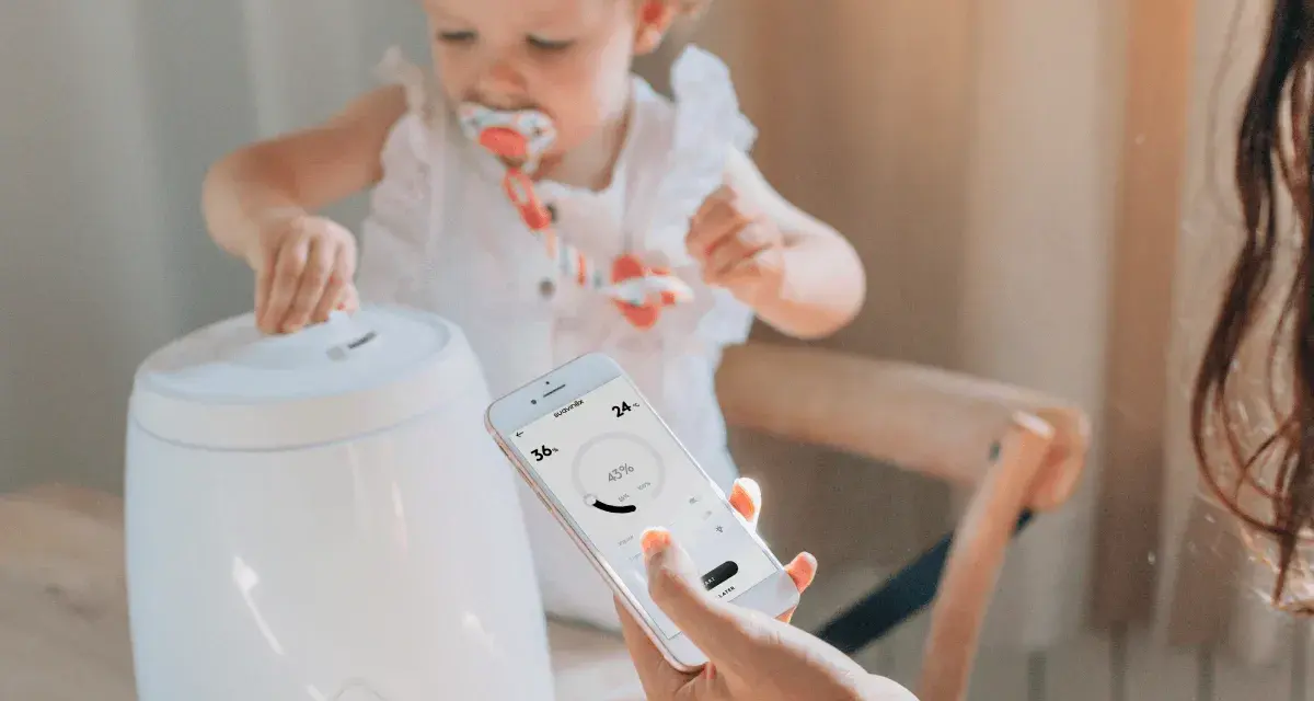 Niña interactúa con humidificador mientras una mano controla la app para humidificar el ambiente.