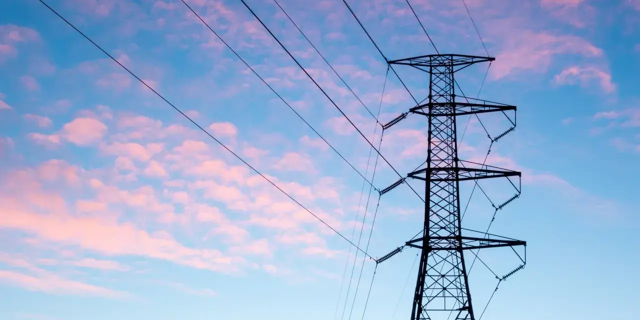 Wieża z przewodami linii energetycznej średniego napięcia na tle różowo-niebieskiego nieba.