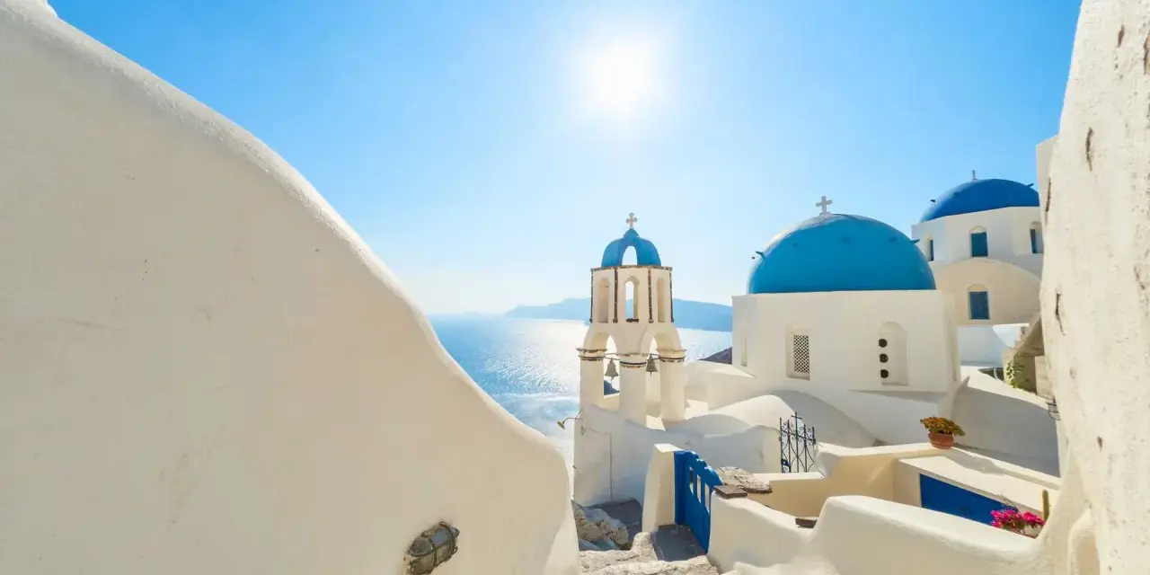 Santorini, październik. Słoneczna pogoda, białe domy i niebieskie kopuły kościołów nad Morzem Egejskim.