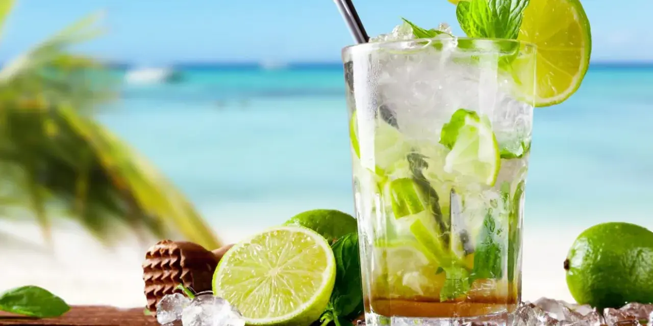 Orzeźwiające drinki z miętą i limonką na tle plaży. Idealne na upalne dni.